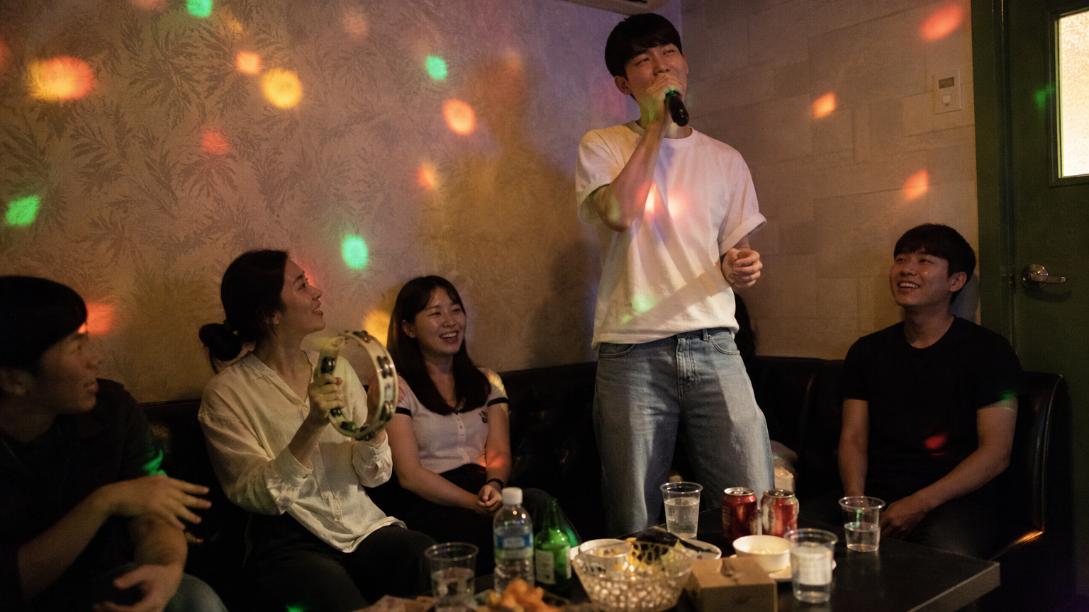A full room: one person sings, another takes the tambourine. Illustrative image.